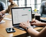 Person Using Macbook Pro on Brown Wooden Desk